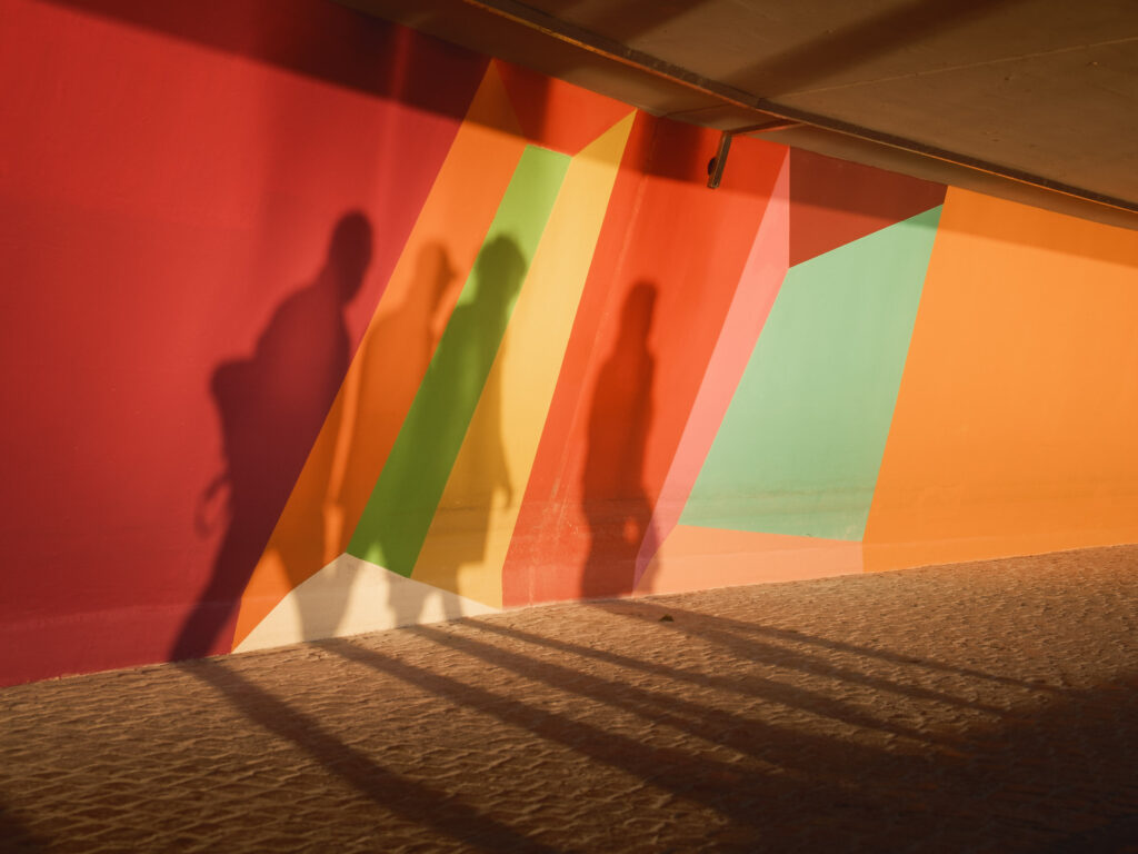 Schatten von Menschen an einer bunten Wand, so bunt wie unsere Emotionen und luftig wie unser Atem.