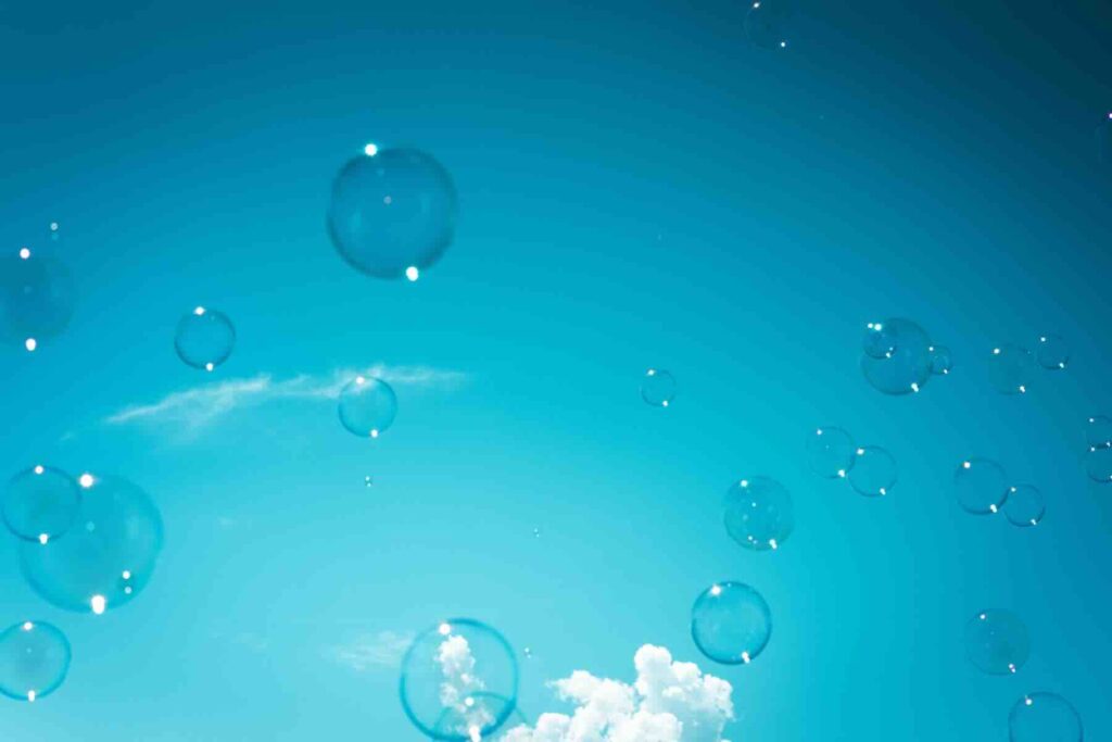 Schimmernde Seifenblasen steigen in den blauen Sommerhimmel auf. Ein Symbol für Ruhe und Loslassen.